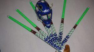 Blauer Hockeyhelm liegt neben mehreren bunten Hockeyschl&auml;gern auf einem hellen Hintergrund.