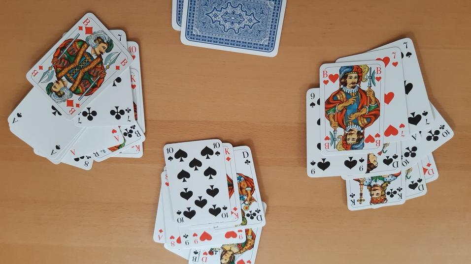 Zwei Stapel Spielkarten auf einem Tisch, ein zus&auml;tzlicher Stapel mit blauer R&uuml;ckseite in der Mitte.