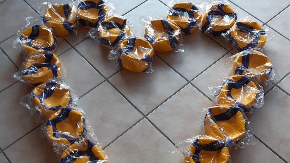 Herzf&ouml;rmige Anordnung aus gelben und blauen Schalen auf einem gefliesten Boden.