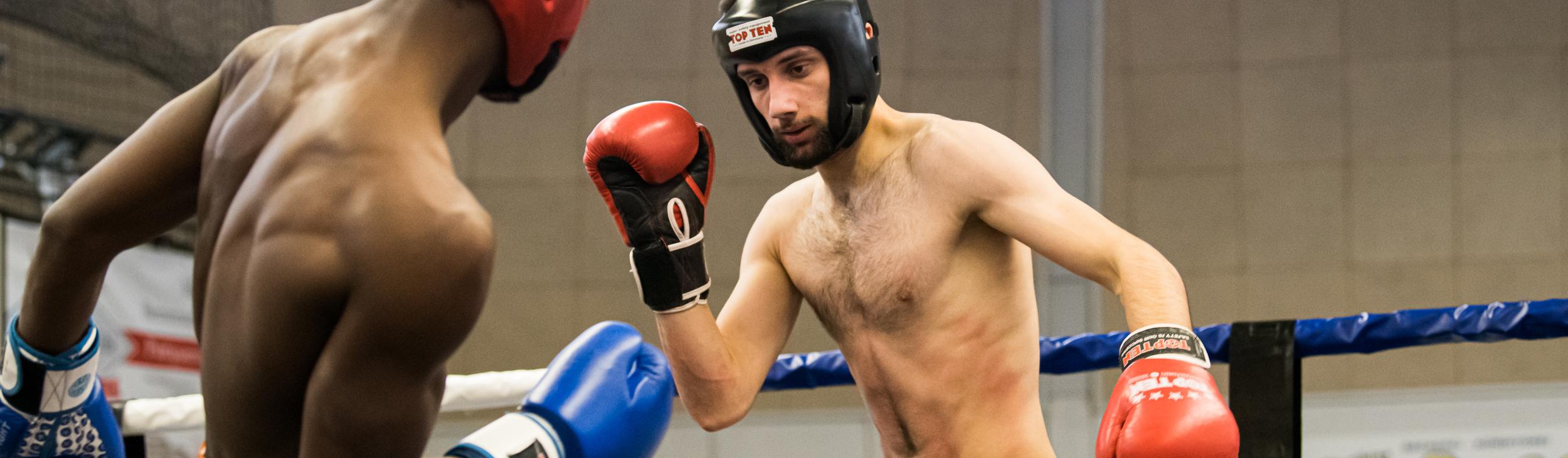 Zwei Boxer im Ring, einer mit roten Handschuhen, der andere mit blauen, bereit für den Kampf.