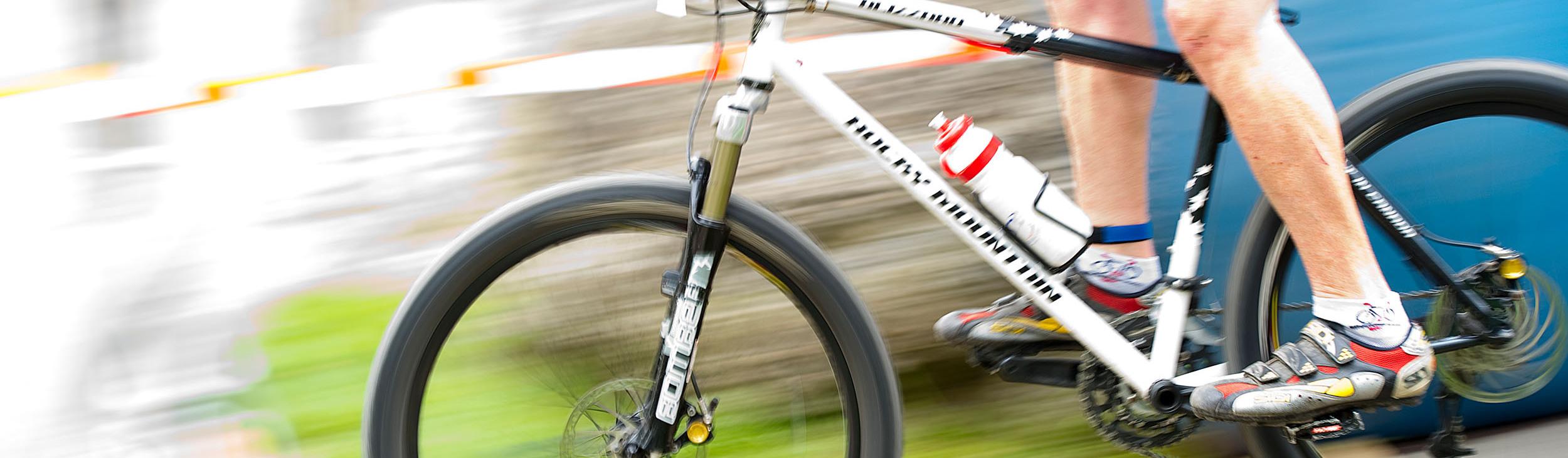 Radsportler fährt mit einem Mountainbike auf einem unebenen Terrain, Wasserflasche am Rahmen, schnelle Bewegung.